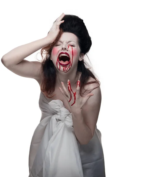 emotional actress brunette woman with pale skin in the role of vampire victims with blood on face on a white background in studio