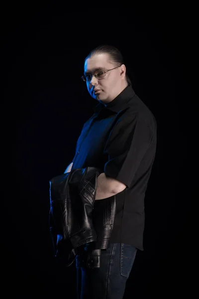 man in black clothes posing on black background with blue light