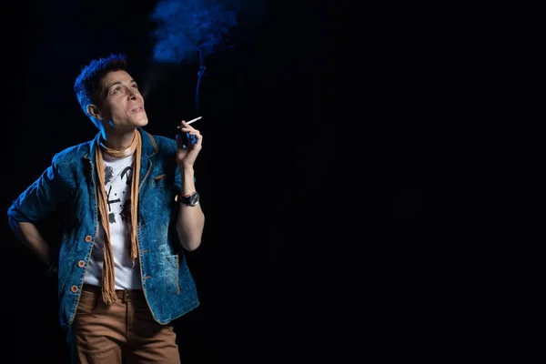 Woman with red hair in a denim suit smoking cigarette and posing on a black background