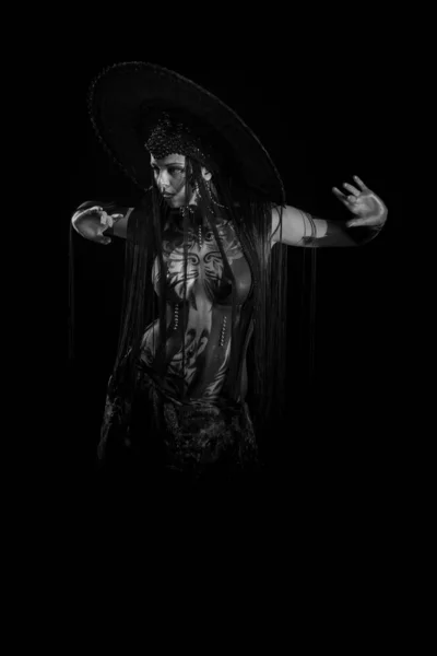 Actress woman in black headdress, body painting, golden figure on body and face, posing on black background