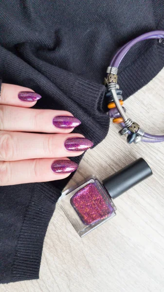 Female hand with long nails with purple nail polish