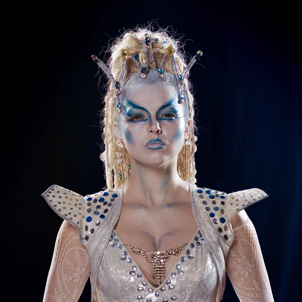 emotional actress woman in makeup and costume of the Snow Queen in the blue-black background