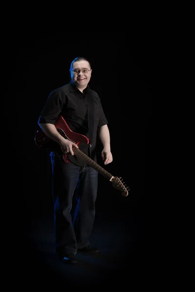 man in black clothes posing on black background with blue light