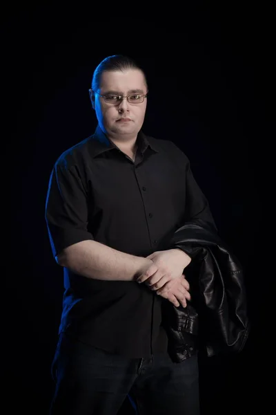 man in black clothes posing on black background with blue light