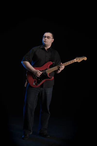 man in black clothes posing on black background with blue light