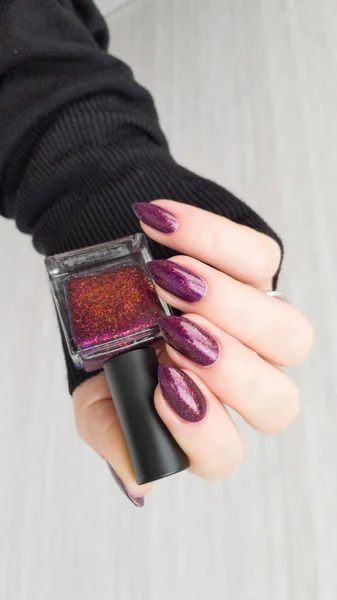 Female hand with long nails with purple nail polish