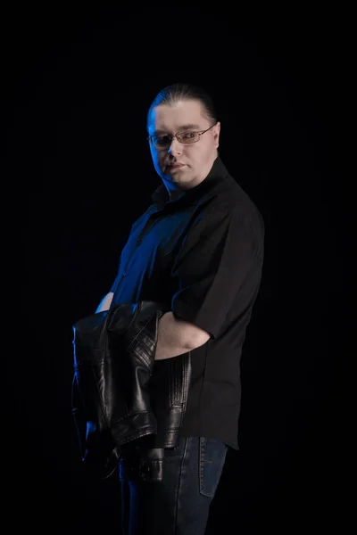 man in black clothes posing on black background with blue light