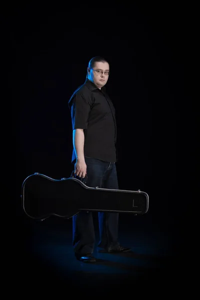 man in black clothes posing on black background with blue light