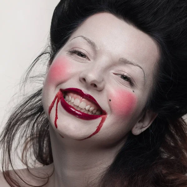 emotional actress brunette woman with pale skin as a vampire with blood on her face on a white background in studio