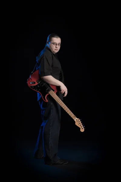 man in black clothes posing on black background with blue light