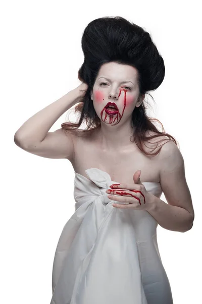 emotional actress brunette woman with pale skin in the role of vampire victims with blood on face on a white background in studio