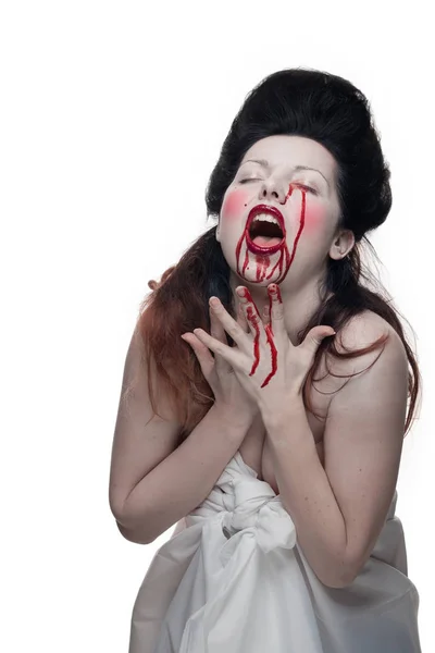 emotional actress brunette woman with pale skin in the role of vampire victims with blood on face on a white background in studio