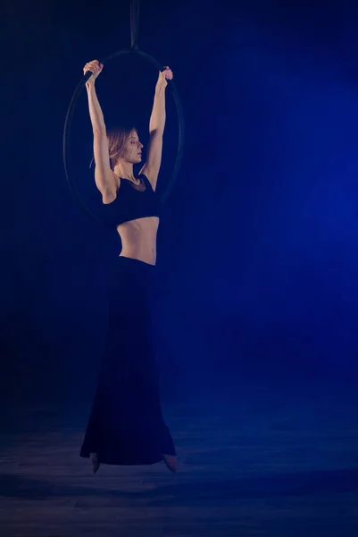 gymnast girl performing acrobatic elements on the ring in dark. Training aerial gymnastics