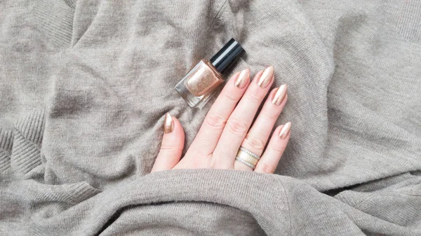 Female hand with long nails with golden nail polish