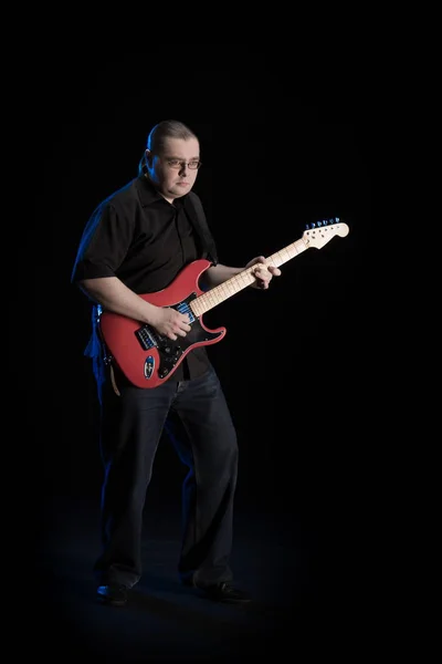 man in black clothes posing on black background with blue light