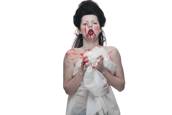 emotional actress brunette woman with pale skin in the role of vampire victims with blood on face on a white background in studio