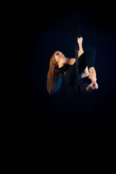 gymnast girl performing acrobatic elements on the ring in dark. Training aerial gymnastics