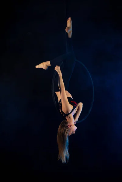 gymnast girl performing acrobatic elements on the ring in dark. Training aerial gymnastics
