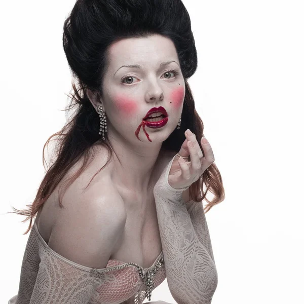 emotional actress brunette woman with pale skin in the role of vampire victims with blood on face on a white background in studio