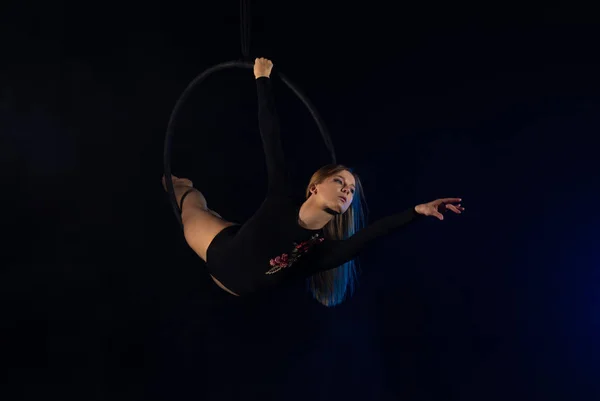 gymnast girl performing acrobatic elements on the ring in dark. Training aerial gymnastics