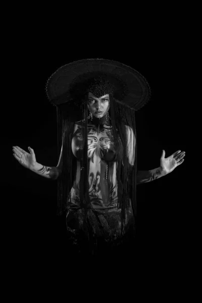 Actress woman in black headdress, body painting, golden figure on body and face, posing on black background