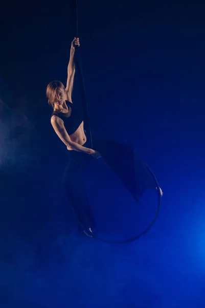 gymnast girl performing acrobatic elements on the ring in dark. Training aerial gymnastics