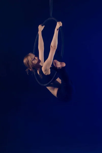 gymnast girl performing acrobatic elements on the ring in dark. Training aerial gymnastics