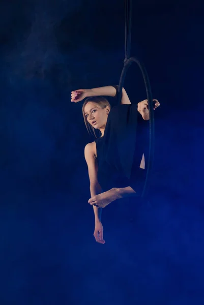 gymnast girl performing acrobatic elements on the ring in dark. Training aerial gymnastics