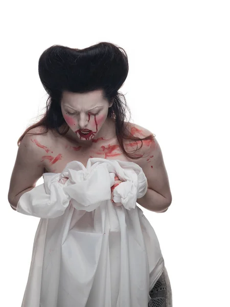 emotional actress brunette woman with pale skin in the role of vampire victims with blood on face on a white background in studio