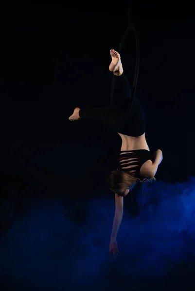 gymnast girl performing acrobatic elements on the ring in dark. Training aerial gymnastics