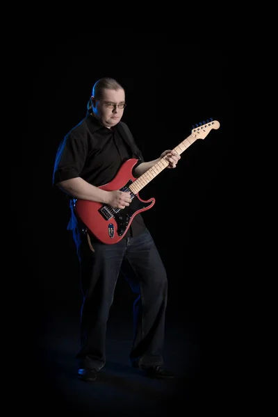 man in black clothes posing on black background with blue light