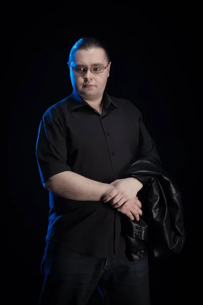 man in black clothes posing on black background with blue light