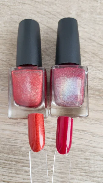 red nail polish palette and bottles on wooden background