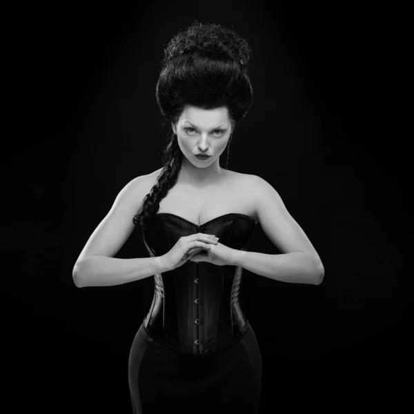 portrait of the actress brunette woman with high hair in a diamond necklace and dress with corset in old style on a black background