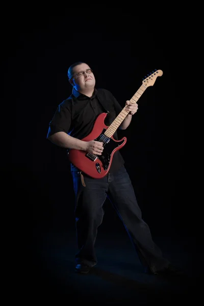 man in black clothes posing on black background with blue light