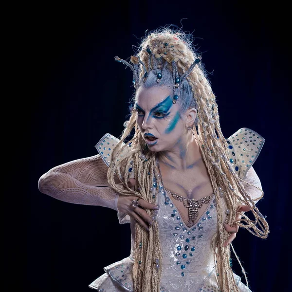 emotional actress woman in makeup and costume of the Snow Queen in the blue-black background