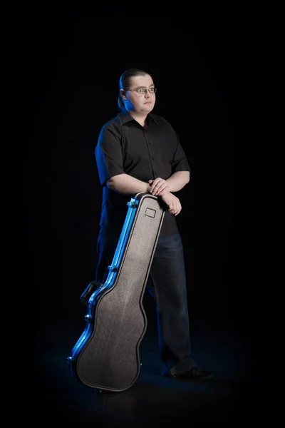 man in black clothes posing on black background with blue light