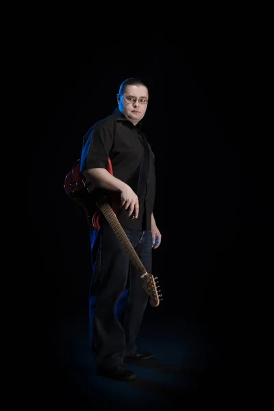 man in black clothes posing on black background with blue light