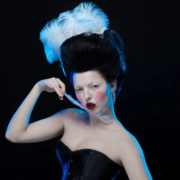 brunette woman with feathers in high hair and corset in old style on a black background