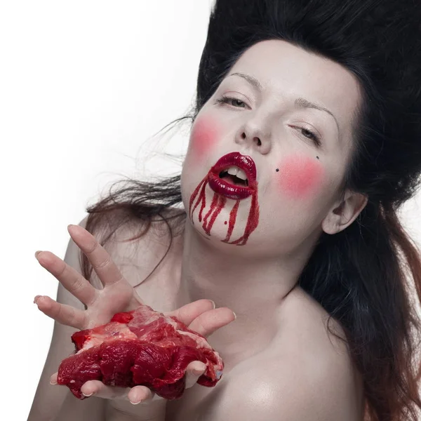 emotional actress brunette woman with pale skin as a vampire with blood on her face on a white background in studio