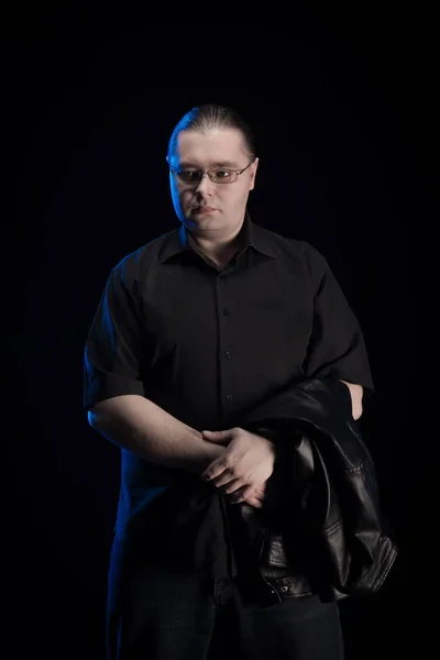 man in black clothes posing on black background with blue light