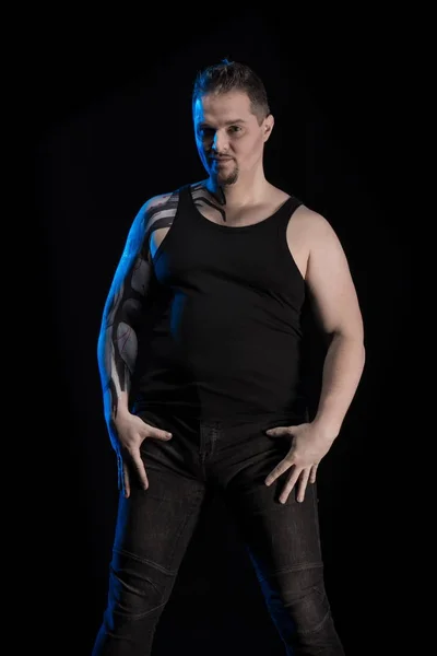 young man in black clothes posing on dark background