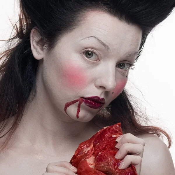 emotional actress brunette woman with pale skin as a vampire with blood on her face on a white background in studio