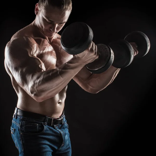 Male athlete bodybuilder posing on dark background