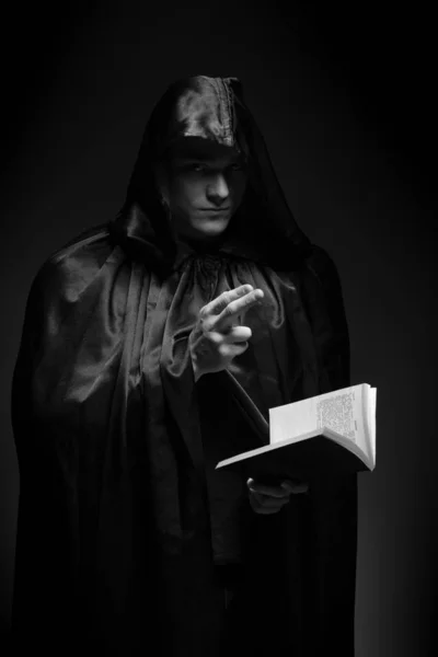 portrait of a brutal young man in a black robe posing in studio