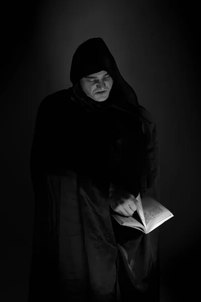 portrait of a brutal young man in a black robe posing in studio