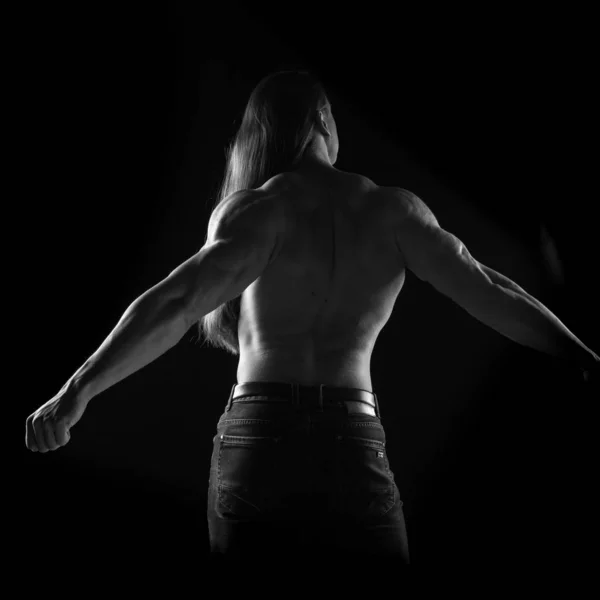 Male athlete bodybuilder posing on black background