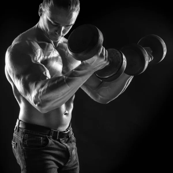 Male athlete bodybuilder posing on black background