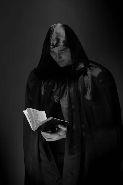 portrait of a brutal young man in a black robe posing in studio