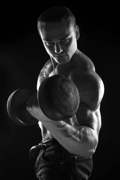 Male athlete bodybuilder posing on black background